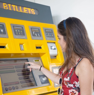 Chica comprando billete FGC en una máquina